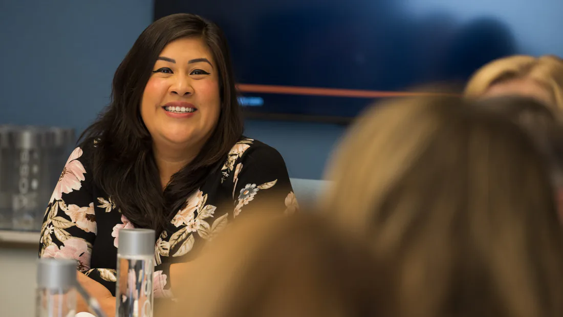 Flor De Maria McNally smiling at a table with real estate professionals