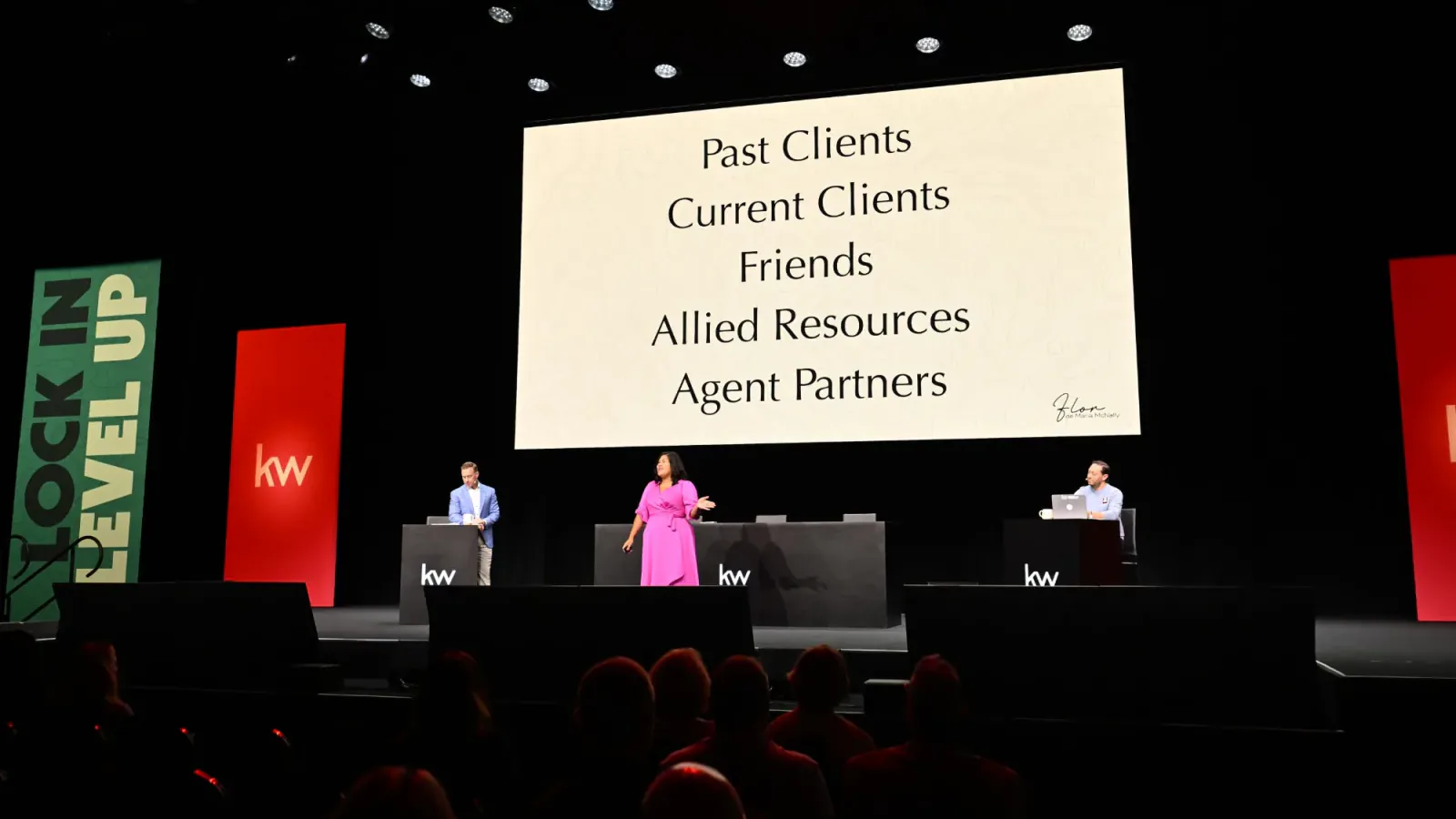 Flor on stage beside her slide listing past clients, current clients, friends, allied resources and agent partners
