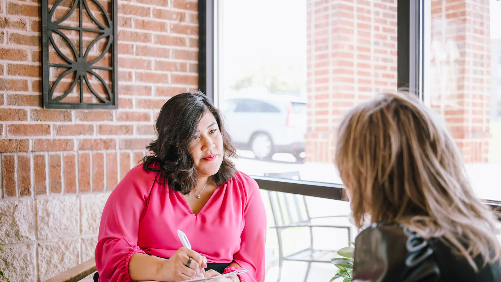Flor De Maria McNally taking notes during a one-on-one conversation
