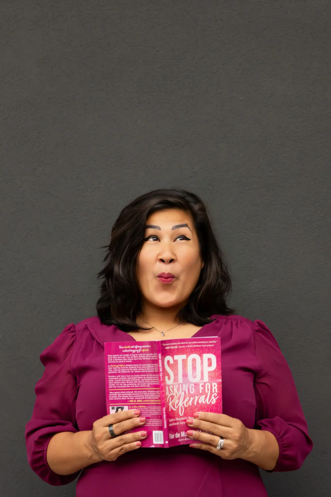 Flor holding her book open and looking up with a playful expression