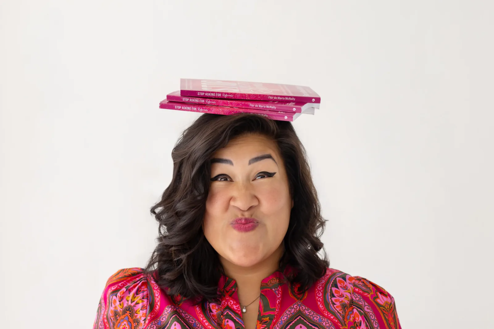 Flor balancing copies of her book on her head